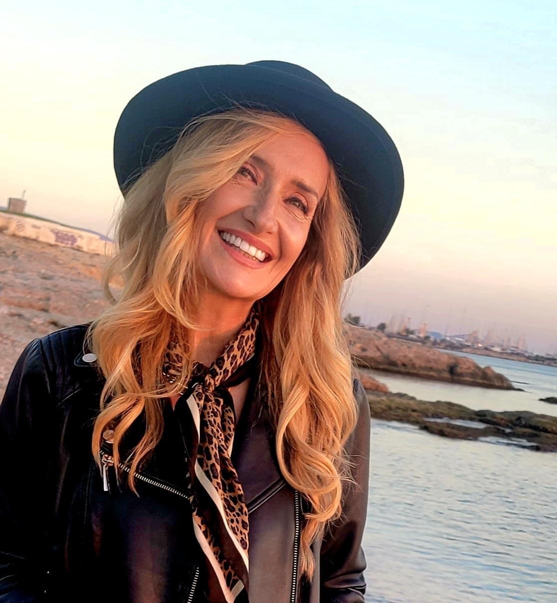 Woman smiling beside the Mediterranean at sunset